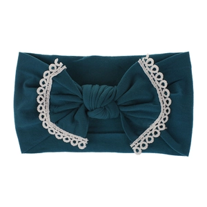 Close-up of soft dark teal nylon baby headband with white lace trim and large bow detail