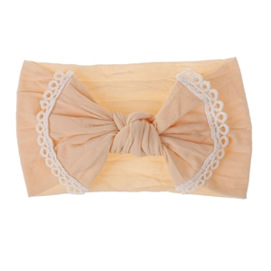 Detail of soft apricot nylon baby headband featuring a large bow and white lace trim