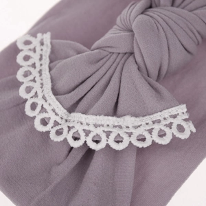 Close-up detail of a soft mauve nylon baby headband featuring elegant white lace trim