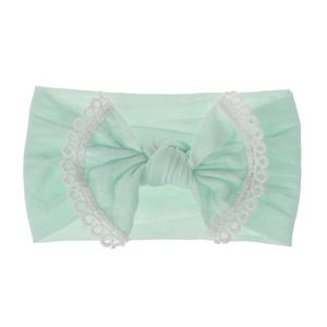 Detailed view of a mint green baby headband featuring a soft nylon bow and lace trim