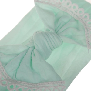 Close-up view of a mint green baby headband featuring a soft nylon bow and lace trim