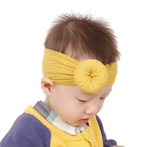 Dettaglio di un neonato che indossa una fascia in nylon giallo senape con nodo a ciambella