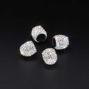 Close-up of four luxury silver crystal rhinestone car tire valve stem caps on black background