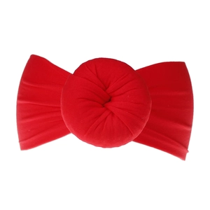 Dettaglio della fascia neonata in nylon rosso con un grande fiocco a forma di ciambella