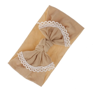 Detailed view of a soft beige baby nylon headband featuring a bow with white lace trim.