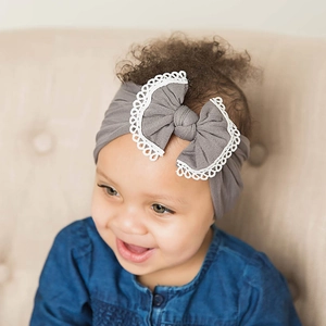 Detailed close-up view of a grey baby headband with soft nylon bow and white lace trim