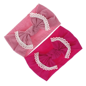 Close-up view of two soft nylon baby headbands with decorative lace-trimmed bows.