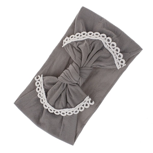 Close-up of a soft nylon baby headband featuring a decorative lace-trimmed bow