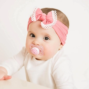 Close-up of a cute baby wearing a soft pink nylon headband with a lace bow detail