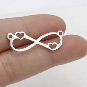 Macro view of polished stainless steel infinity pendant with hollow hearts held by fingers