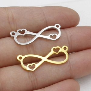 Macro view of gold and silver infinite heart connector pendants on fingers