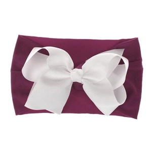 Detail eines weichen Nylon-Babystirnbands mit großer weißer Schleife auf burgunderfarbenem Band