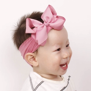 Nahaufnahme eines lächelnden Babys mit einem weichen rosa Nylon-Schleifen-Stirnband