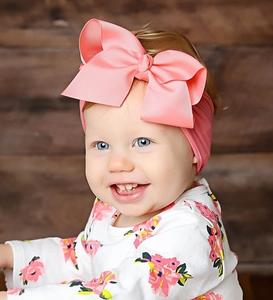 Detailansicht eines Baby-Stirnbands mit großer, hellrosa Schleife aus weichem Nylon