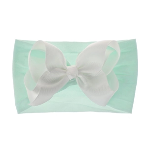 Detail eines Baby Stirnbandes aus Nylon mit großer weißer Ripsbandschleife auf Minzgrün