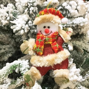 Detail eines Plüsch-Schneemann-Weihnachtsanhängers an einem verschneiten Ast