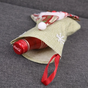 Détail d'une chaussette de Noël verte avec motif Père Noël et une bouteille dedans