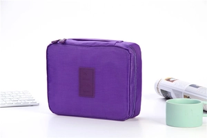 Purple travel toiletry bag with zipper and handle on a white desk workspace setting