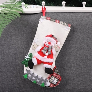 Linen Christmas stocking with 3D snowman and red plaid details hanging on a grey wall