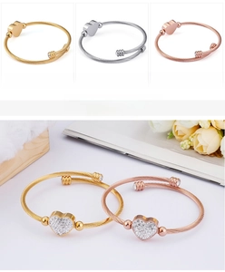 Detailed view of heart charms on woven steel cable bracelets in three metallic finishes