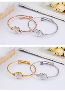 Detailed macro of woven wire bracelets with heart crystal charms in three metal colors