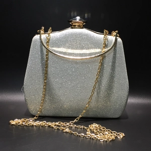 Close-up of silver sequin evening bag with gold metal handle and chain on black background