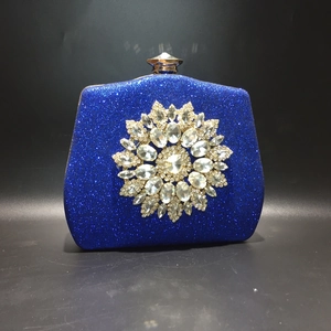 Close-up of sparkling blue evening clutch bag with a large sunflower rhinestone ornament