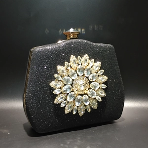Macro shot of sparkling black fabric and oversized rhinestone flower on an evening clutch