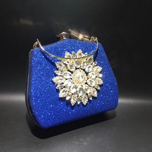 Close-up of sparkling blue evening clutch with sunflower rhinestone ornament and metal handle
