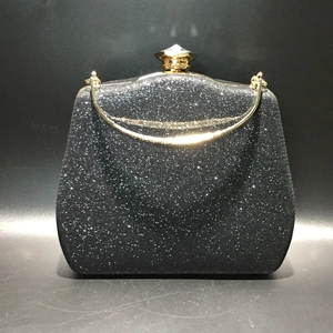 Detail of black glitter evening clutch with golden metal clasp and curved handle