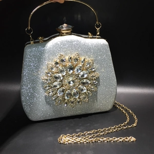 Close-up of silver sequin evening bag with crystal floral motif and gold metal handle