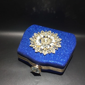 Detail of blue sequin evening clutch bag with crystal sunflower ornament and gold frame