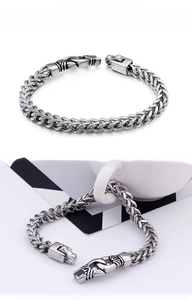 Close-up of polished silver stainless steel spiga chain bracelet with engraved clasp