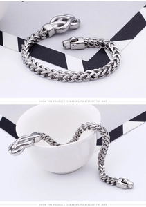 Macro detail of men's stainless steel wheat chain bracelet with decorative knot clasp