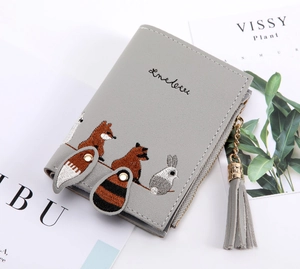 Detail of grey short wallet with forest animal embroidery and tassel zipper charm