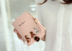 Close-up of pink folding wallet with cute animal embroidery and tassel pendant detail