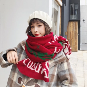 Detail of red and green knitted Christmas scarf with festive patterns on a model