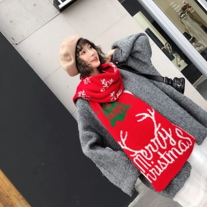 Detail view of red knitted Christmas scarf with white reindeer patterns and festive text