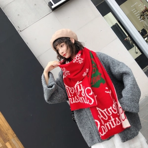 Detail of red knitted Christmas scarf with white Merry Christmas text and snowflake patterns