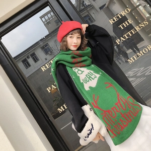 Detail of green knitted scarf with red Christmas reindeer and letter patterns on model