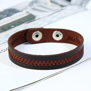 Brown woven leather bracelet with metal snap button closure on a magazine background
