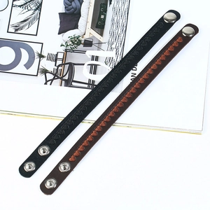 Detail view of black and brown leather bracelets with embroidered heart patterns and snap button