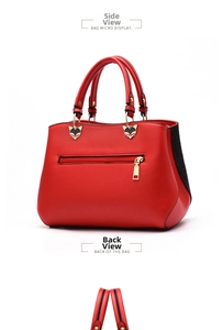Detail view of red lychee grain handbag with black contrast sides and cat-shaped hardware