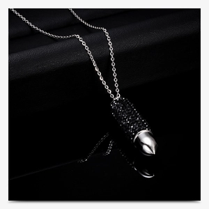 Macro shot of silver bullet pendant featuring black crystals on a reflective surface