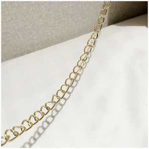 Macro shot of the glossy golden metal chain strap with drop-shaped links on a soft cat paw bag