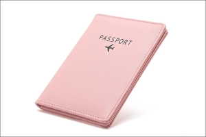Detailed view of pink leather passport holder with embossed text and airplane icon