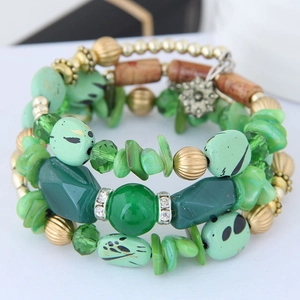 Detail of multi-layered beaded bracelet set with green stones and vintage flower charm