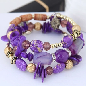 Détail d'un bracelet bohème multicouche avec cristaux violets et pendentif flocon de neige