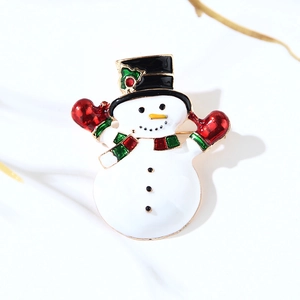 Macro shot of a Christmas snowman enamel brooch with red gloves and green scarf details