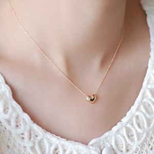 Elegant gold heart pendant necklace on thin chain worn with white lace top for women